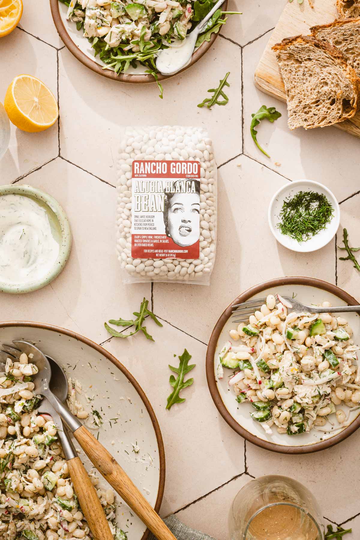 various serving plates and a larg bowl with the white bean salad, bag with dry bans