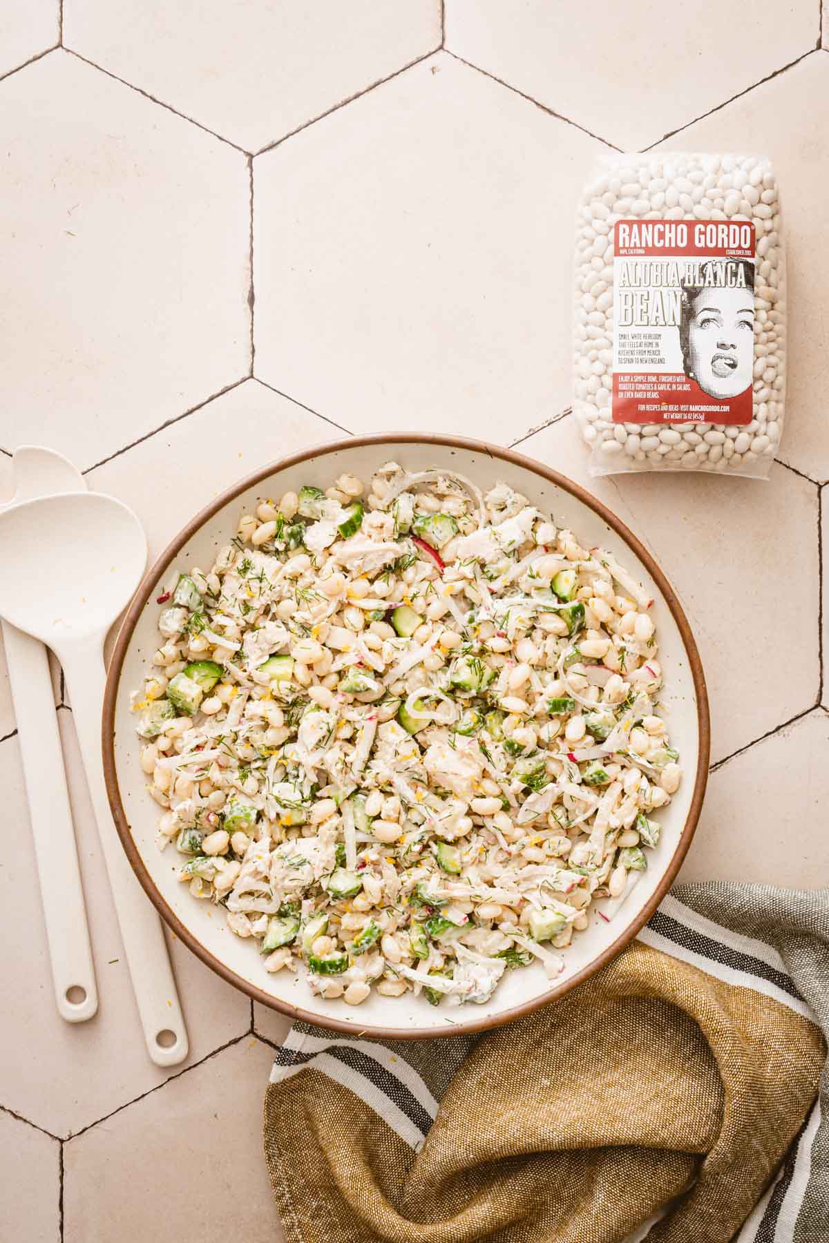 large bowl with salad and a bag with dry beans, serving utensils