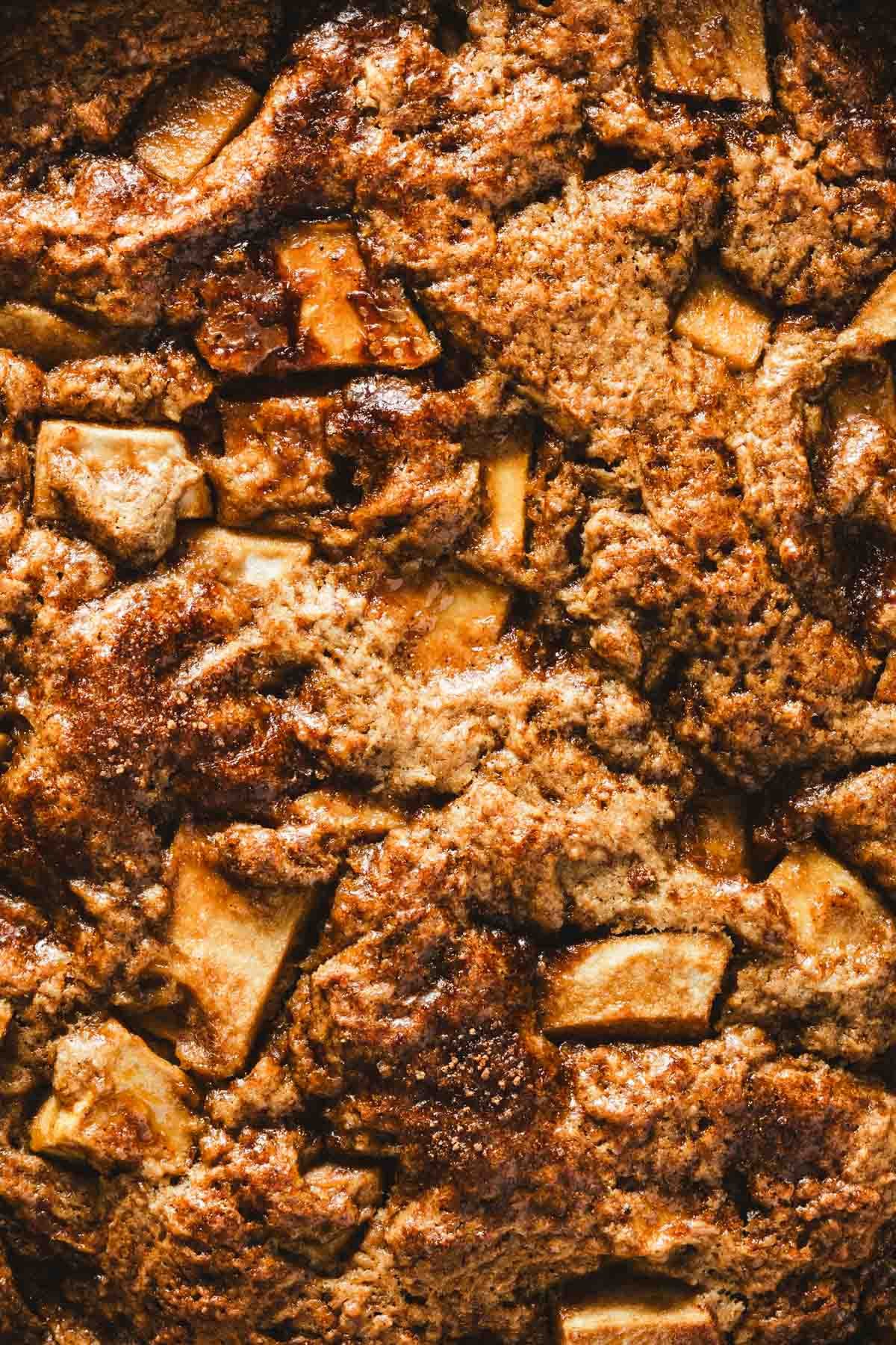 Close-up of the crackly cinnamon sugar crust on a brown butter apple cake, showing caramelized apple pieces.
