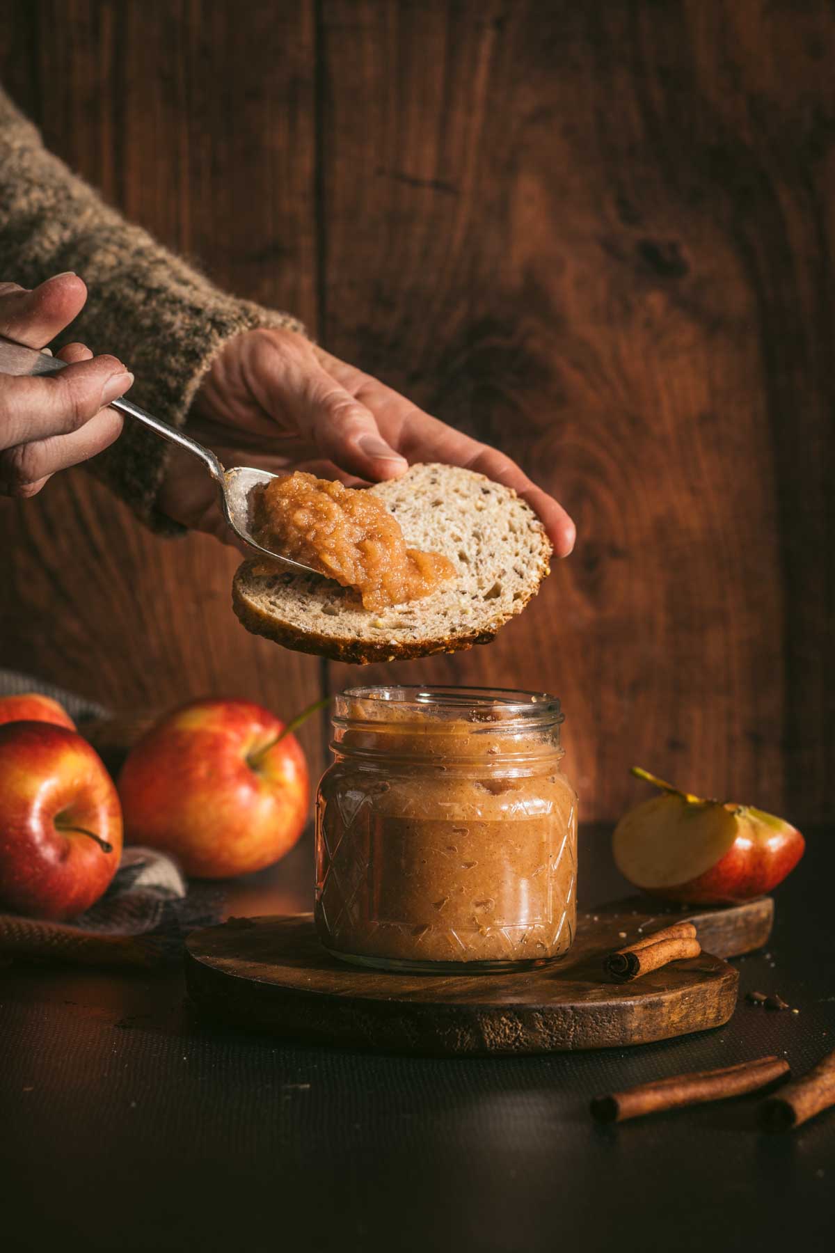 hand in frame applying apple butter onto the toast