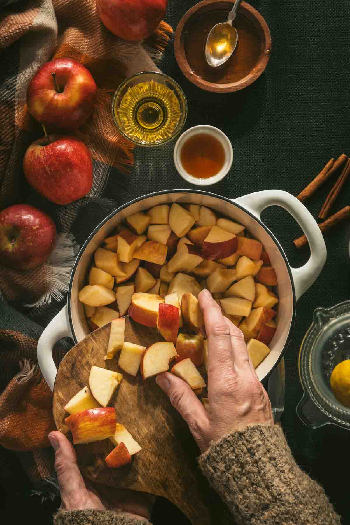 cut apples in a saucepan, hand in frame