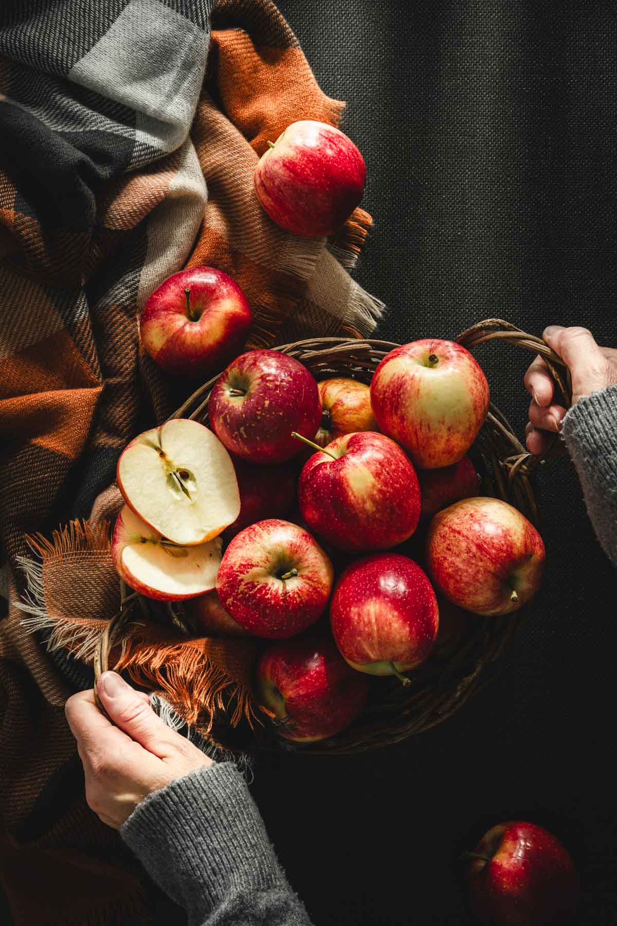 hands holding basket filled with apples