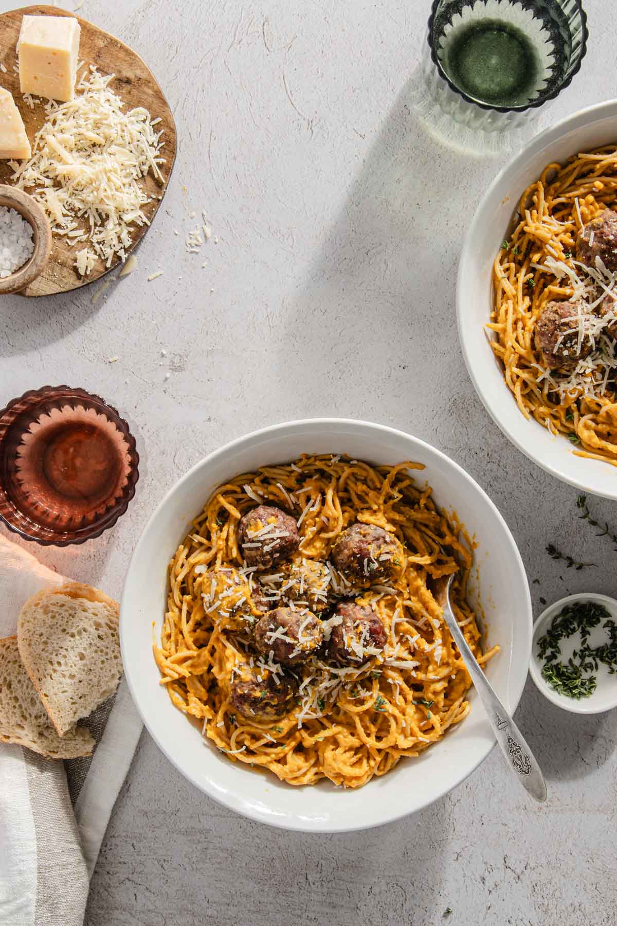 meatballs atop of noodles with sauce, glass with water, another bowl with meatballs