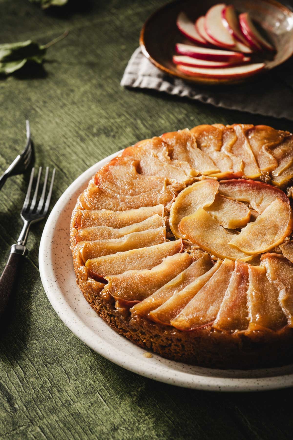 Angled close-up of glossy caramelized apple slices arranged in a spiral on an apple upside down cake.