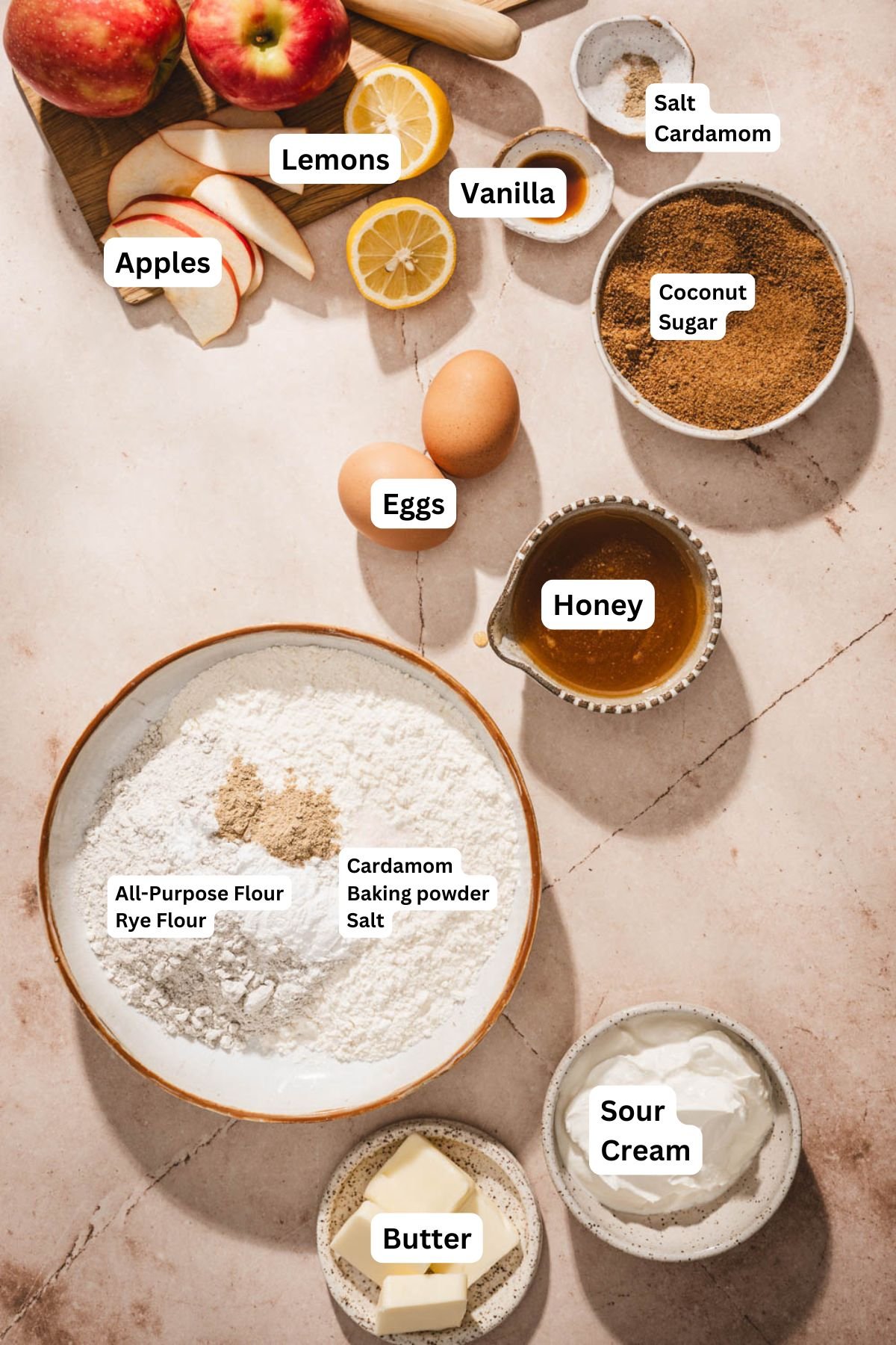 Ingredients for apple upside down cake: flour with spices, brown sugar, eggs, butter, yogurt, vanilla, lemon, and apples.