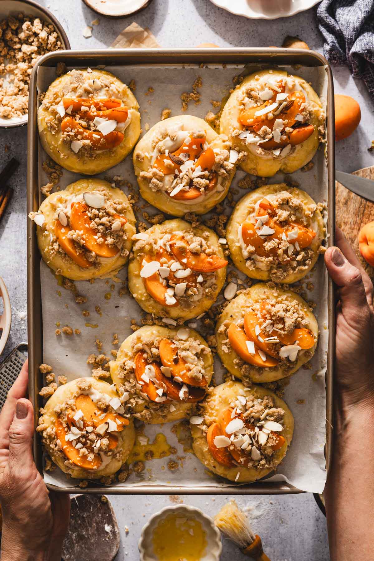 hands holding baking sheet with sweet buns