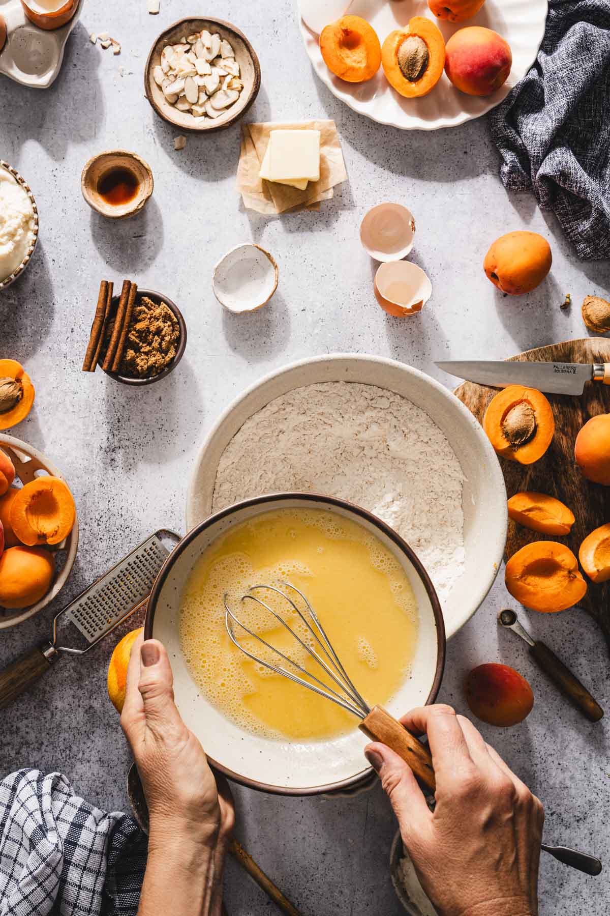 hands in frame holding bowl with wet ing over a bowl with flour