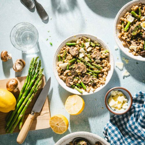 serving bowl with the risotto, cutting board with fresh asparagus