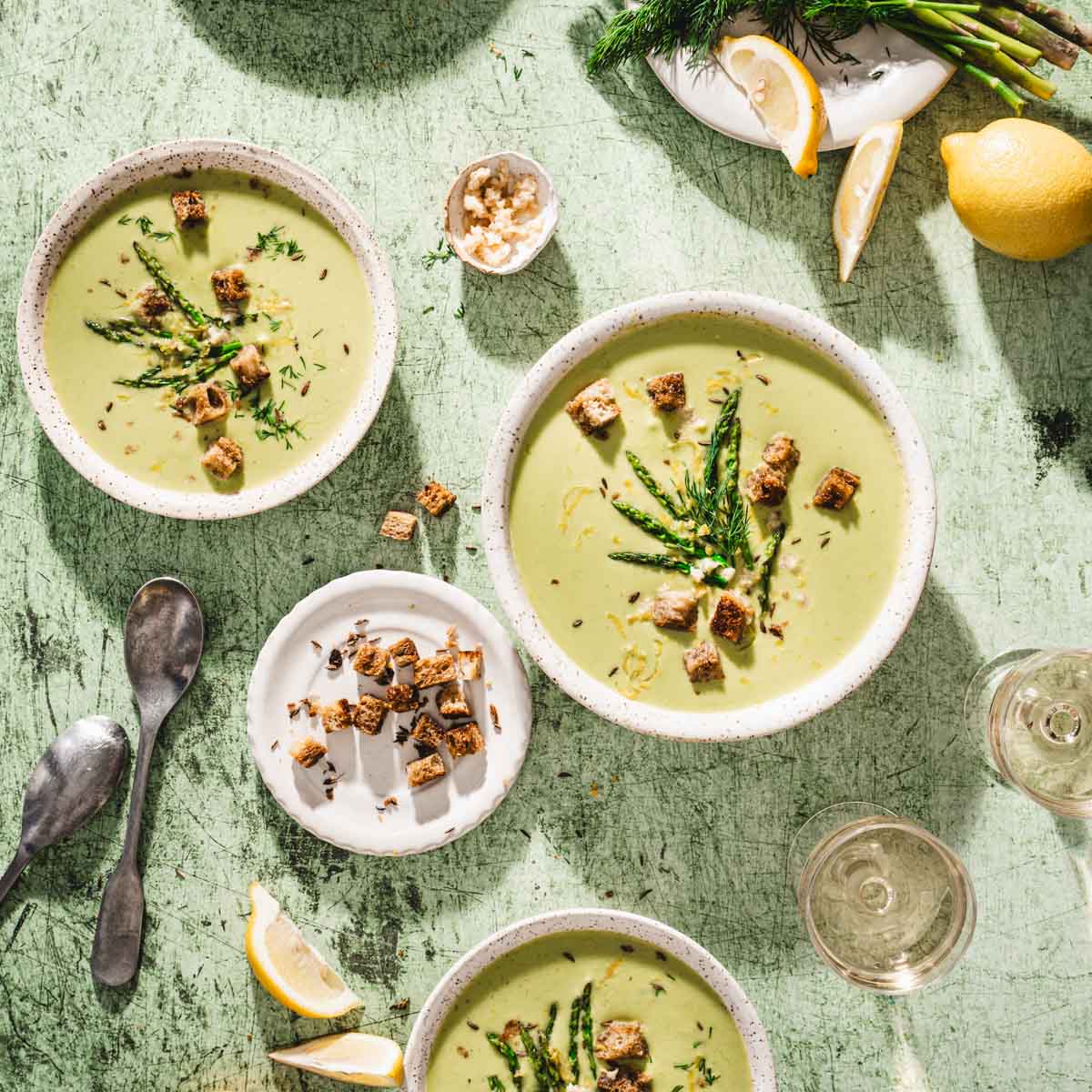various serving bowls with soup, spoons, lemon wedges