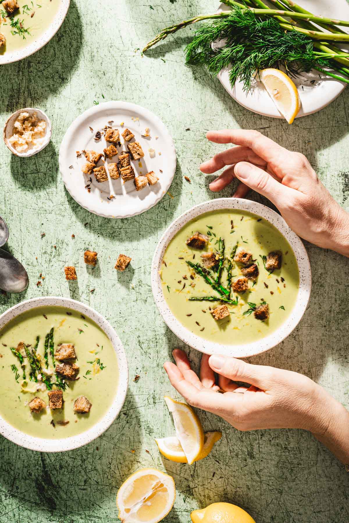 hands in frame holding bowl with soup, dish with croutons