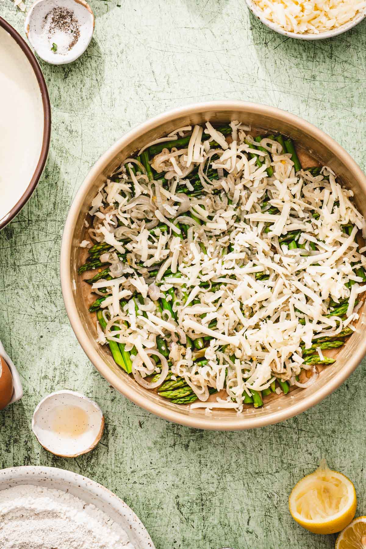 cake pan with shallots and cheese added on top of the asparagus
