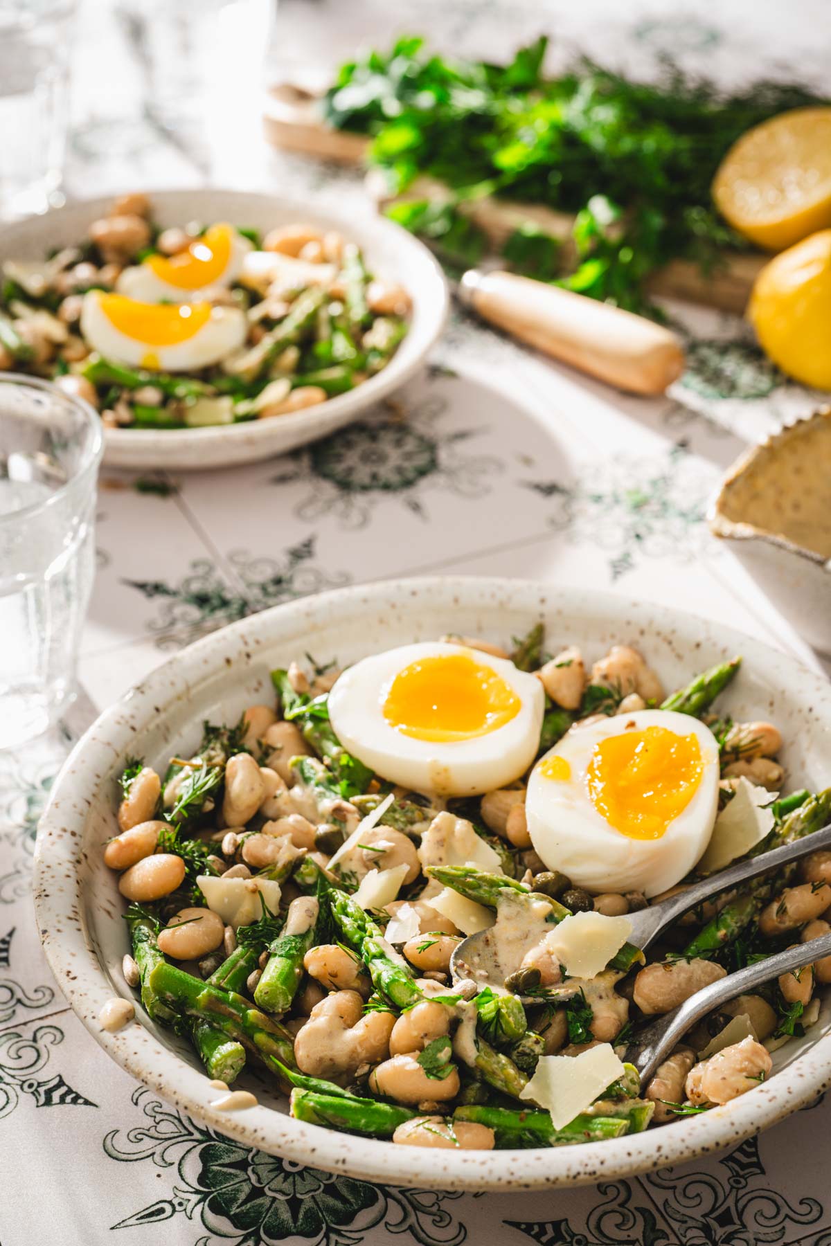 side view of the bowl with salad, glass iwth water, board with greens