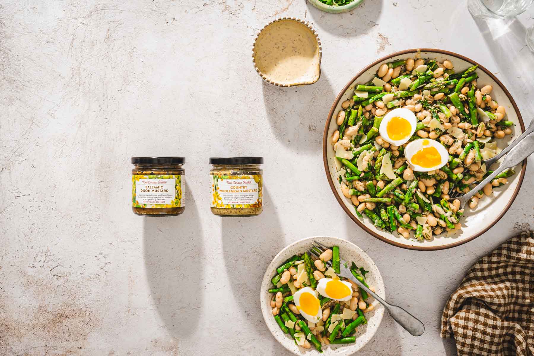 horizontal photo, bowl with asparagus salad, small serving bowl, brand jars, dish with dressing
