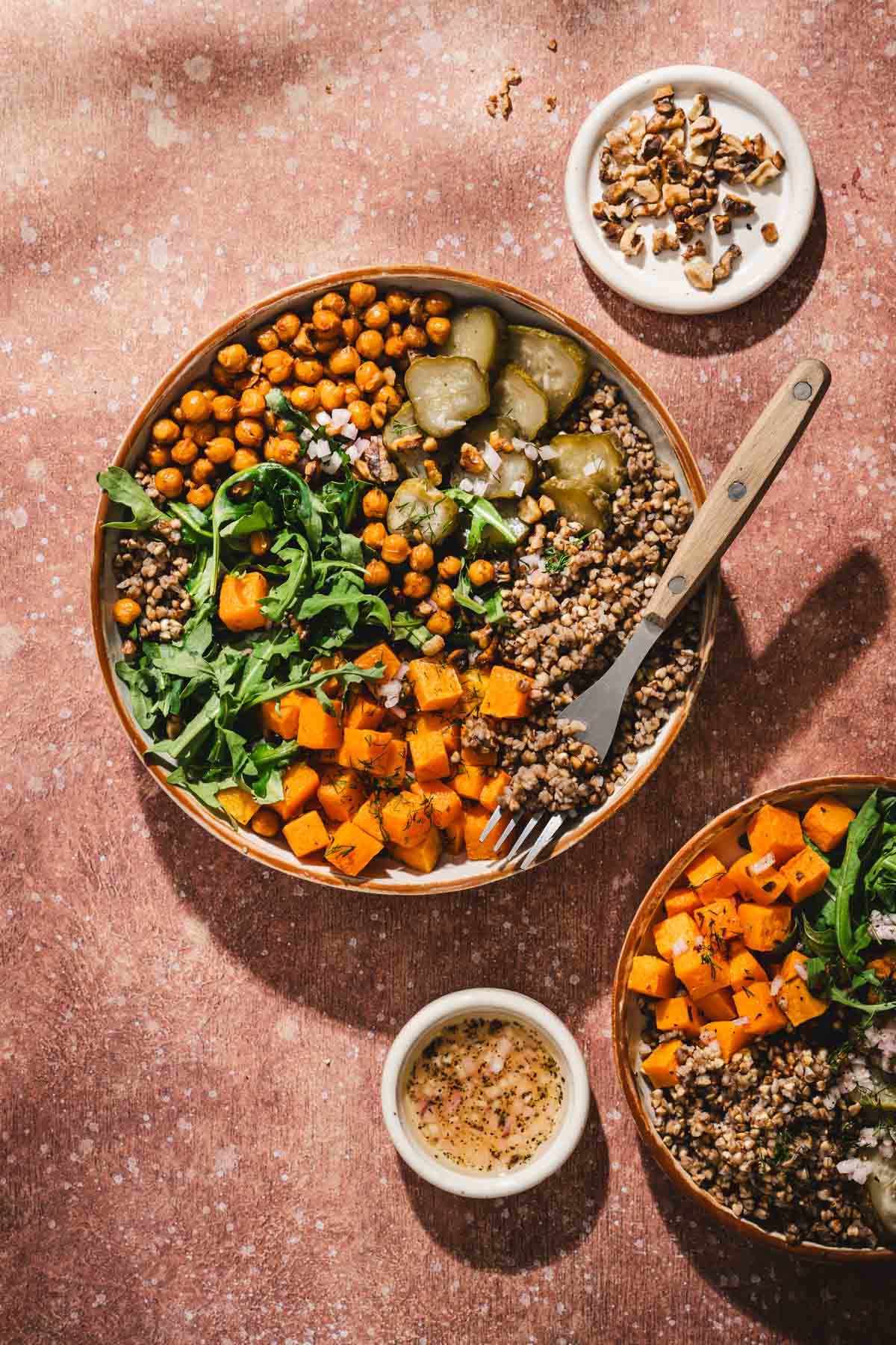 top view of buckwheat squash bowls, dish with walnuts, fork