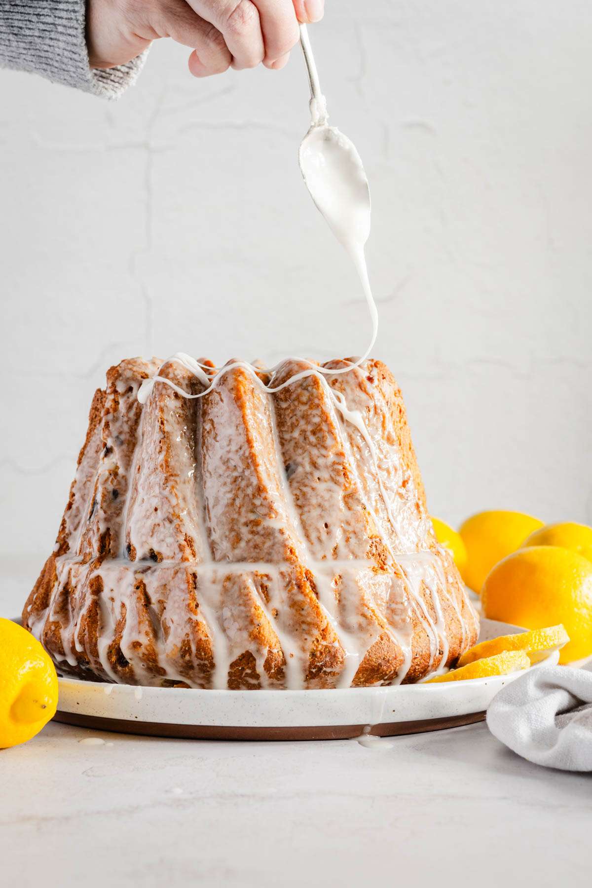 whole babka, front view, hands in frame drizzling the frosting