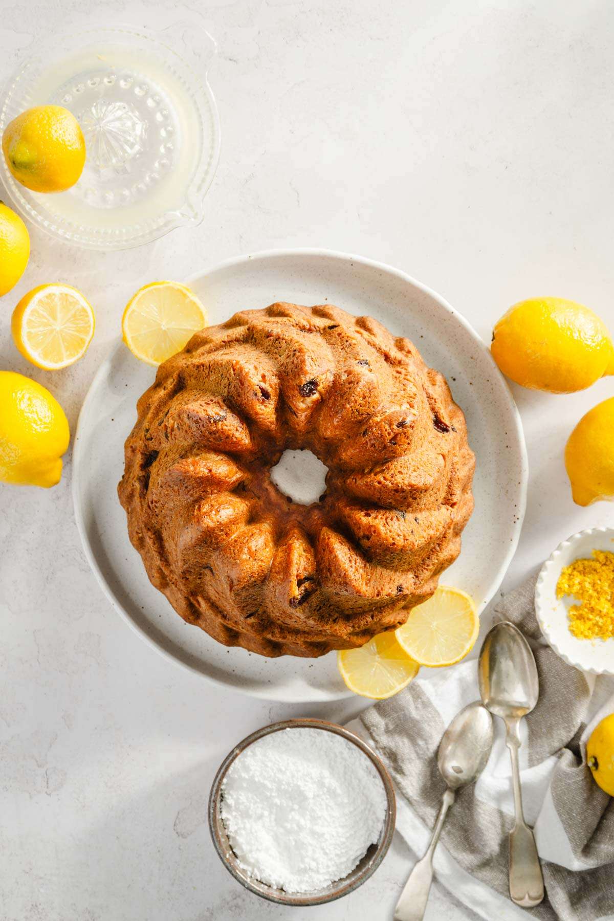 top view of baked babka, lemons around, bowl with powdered sugar