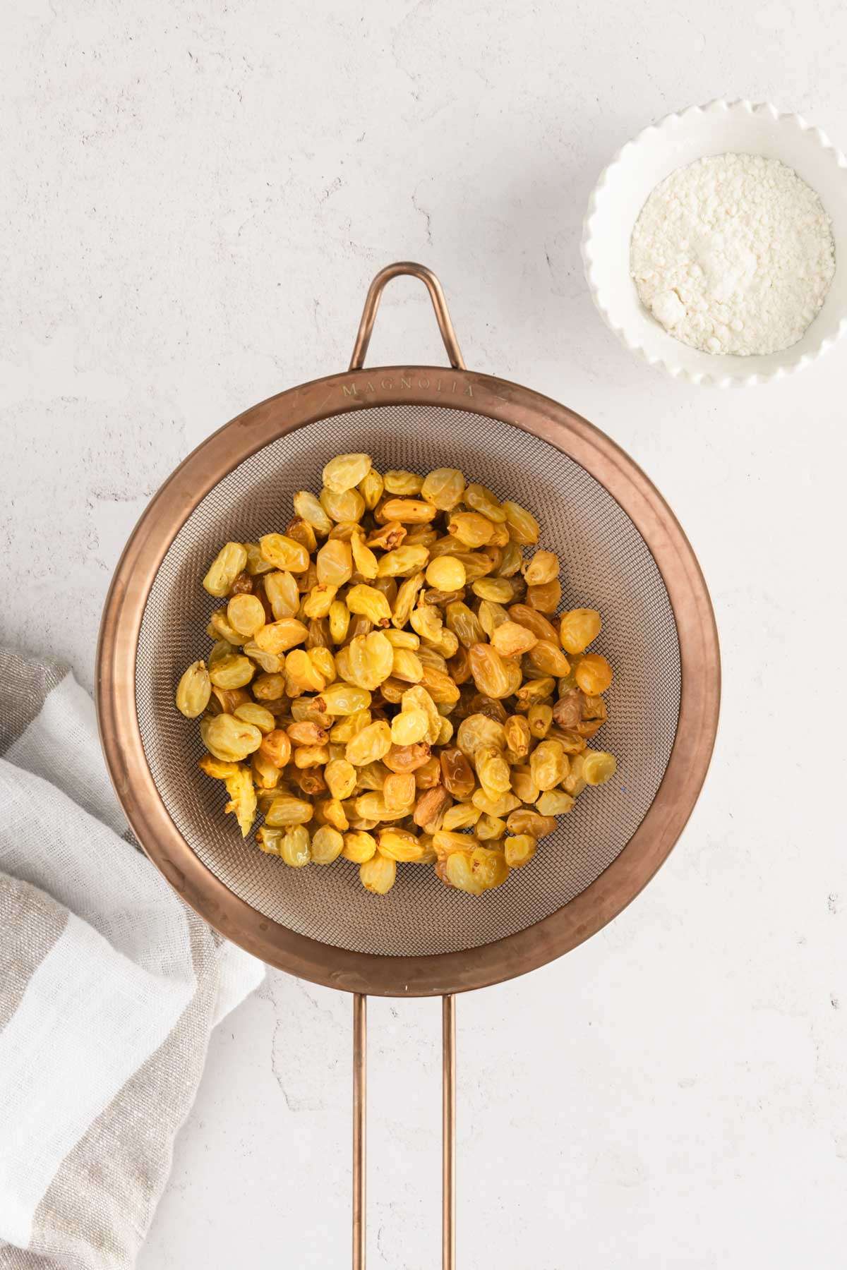 raisins in a strainer, small bowl with flour