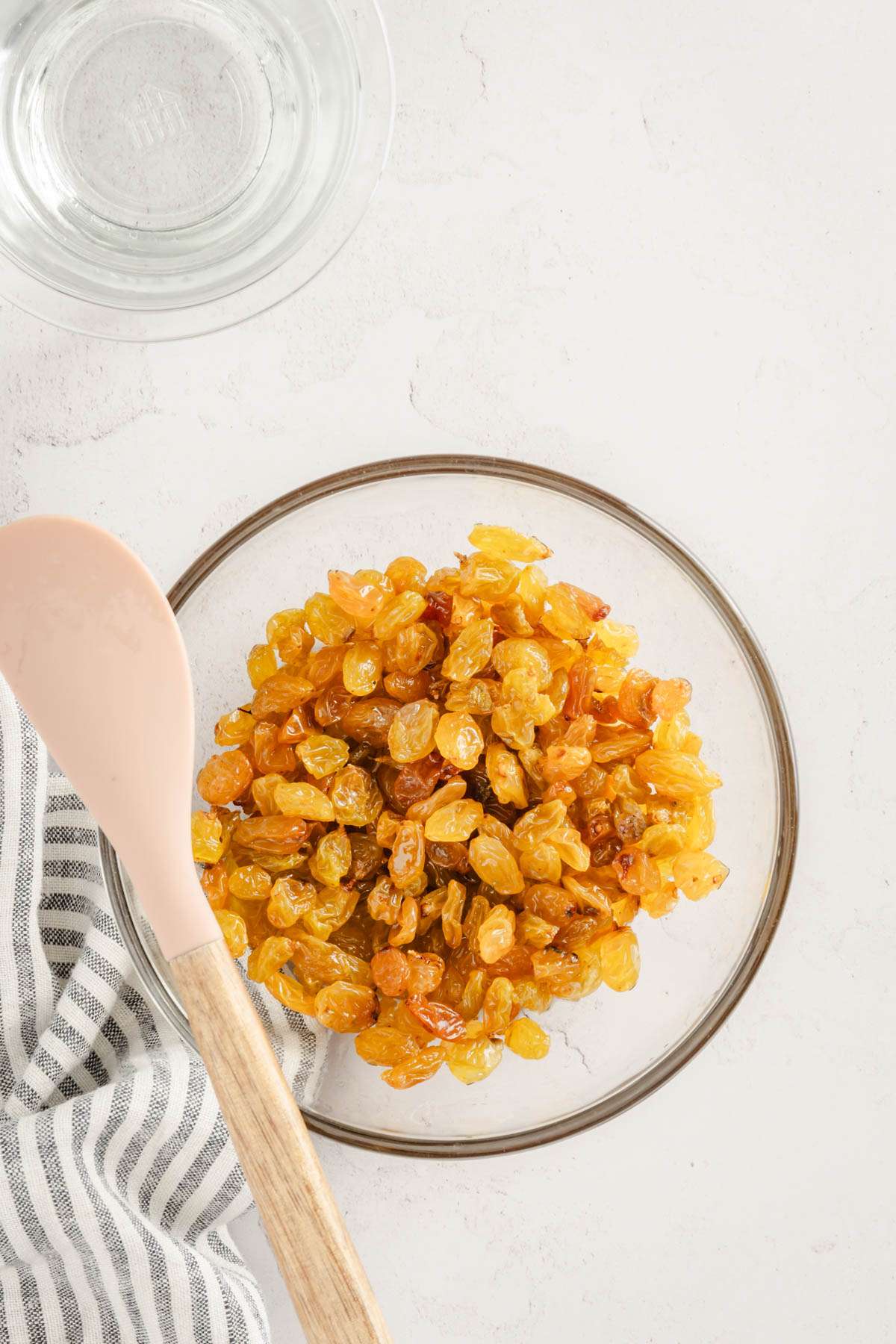 raisins in a glass bowl, glass with water on the side