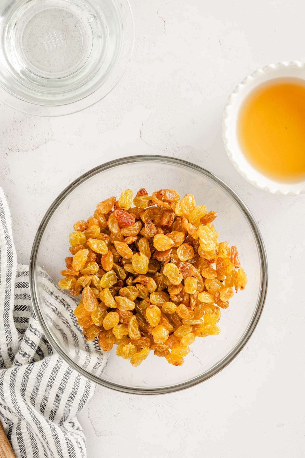 raisins in a bowl, glass with water and one with brandy