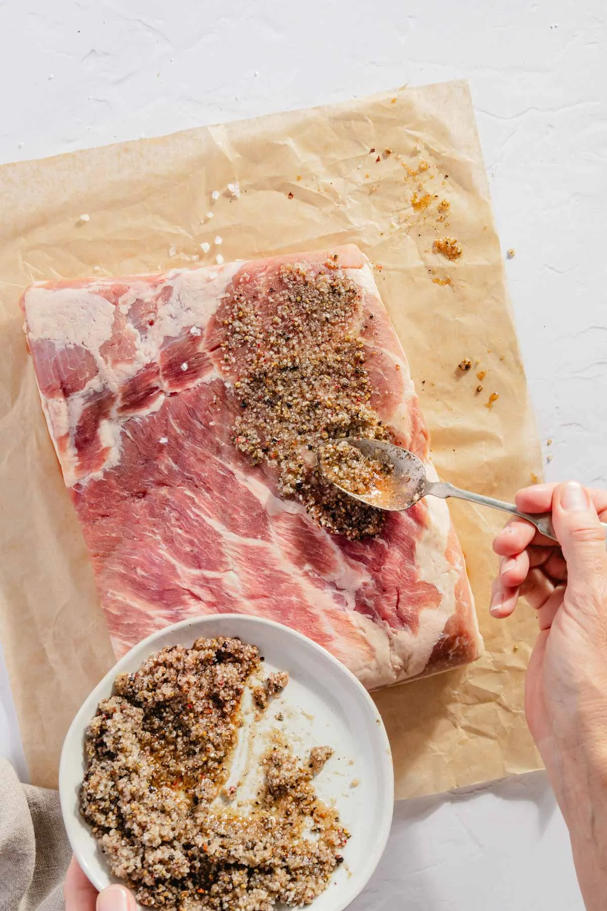 hand in frame applying cure to the pork belly