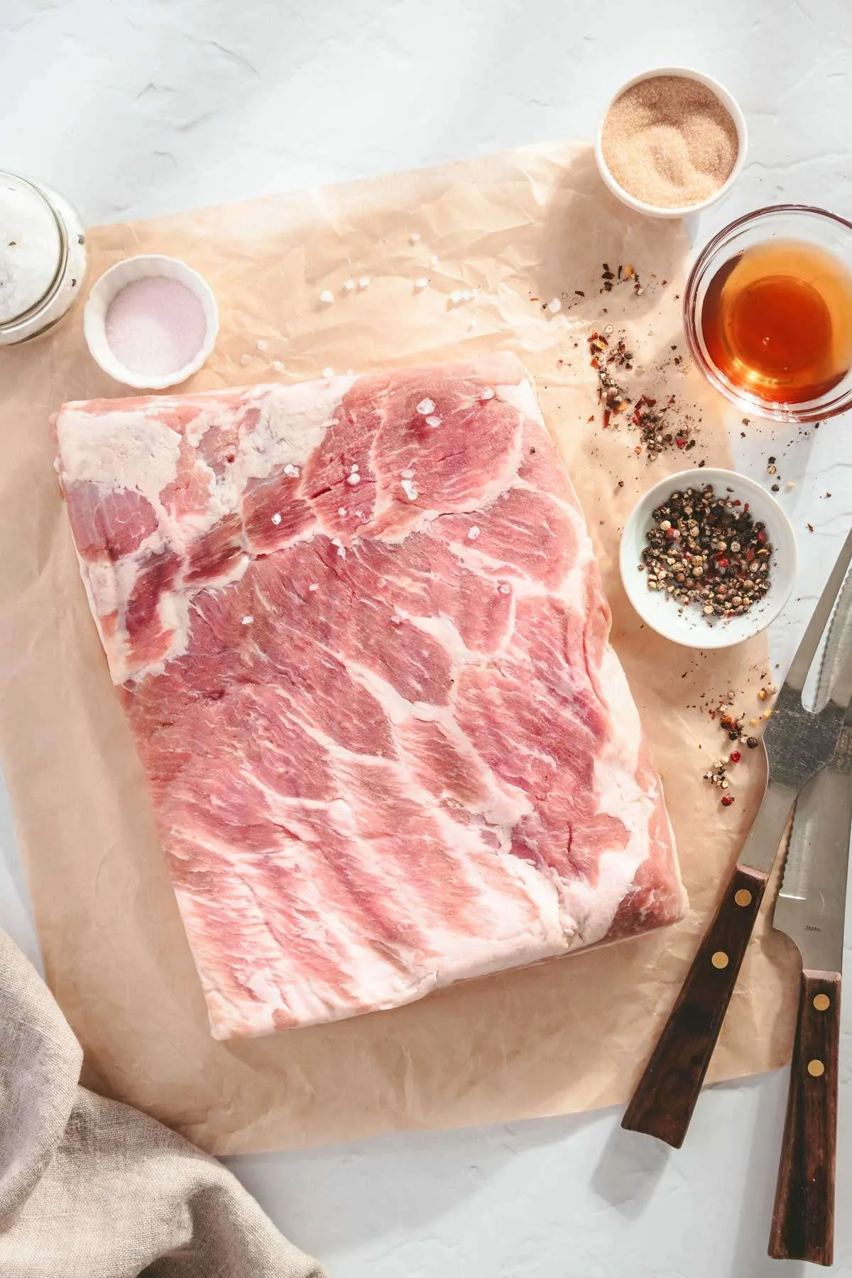 ingredients to make bacon; slab of pork belly with small dishes around