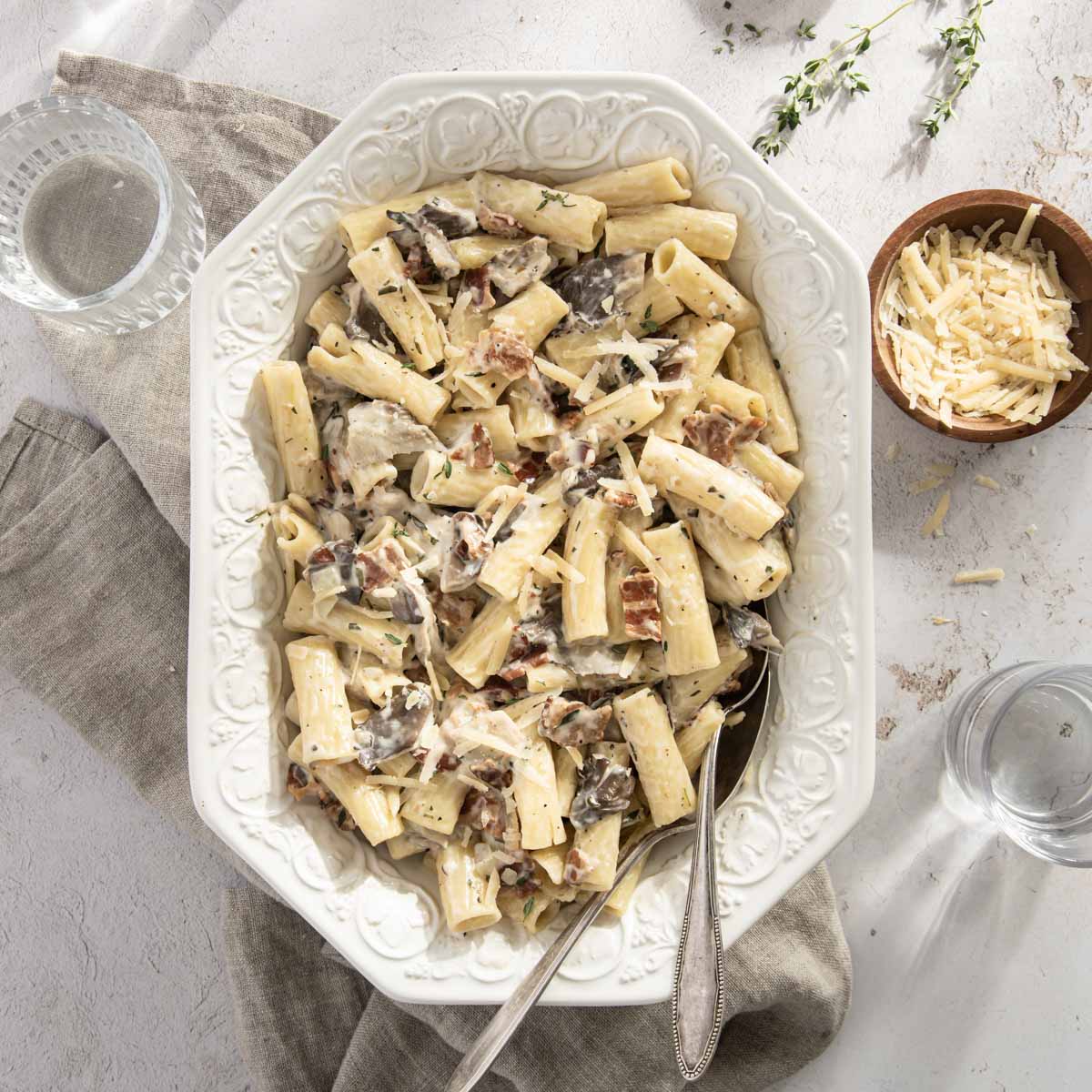 pasta in a serving dish, small bowl with shredded parmesan cheese