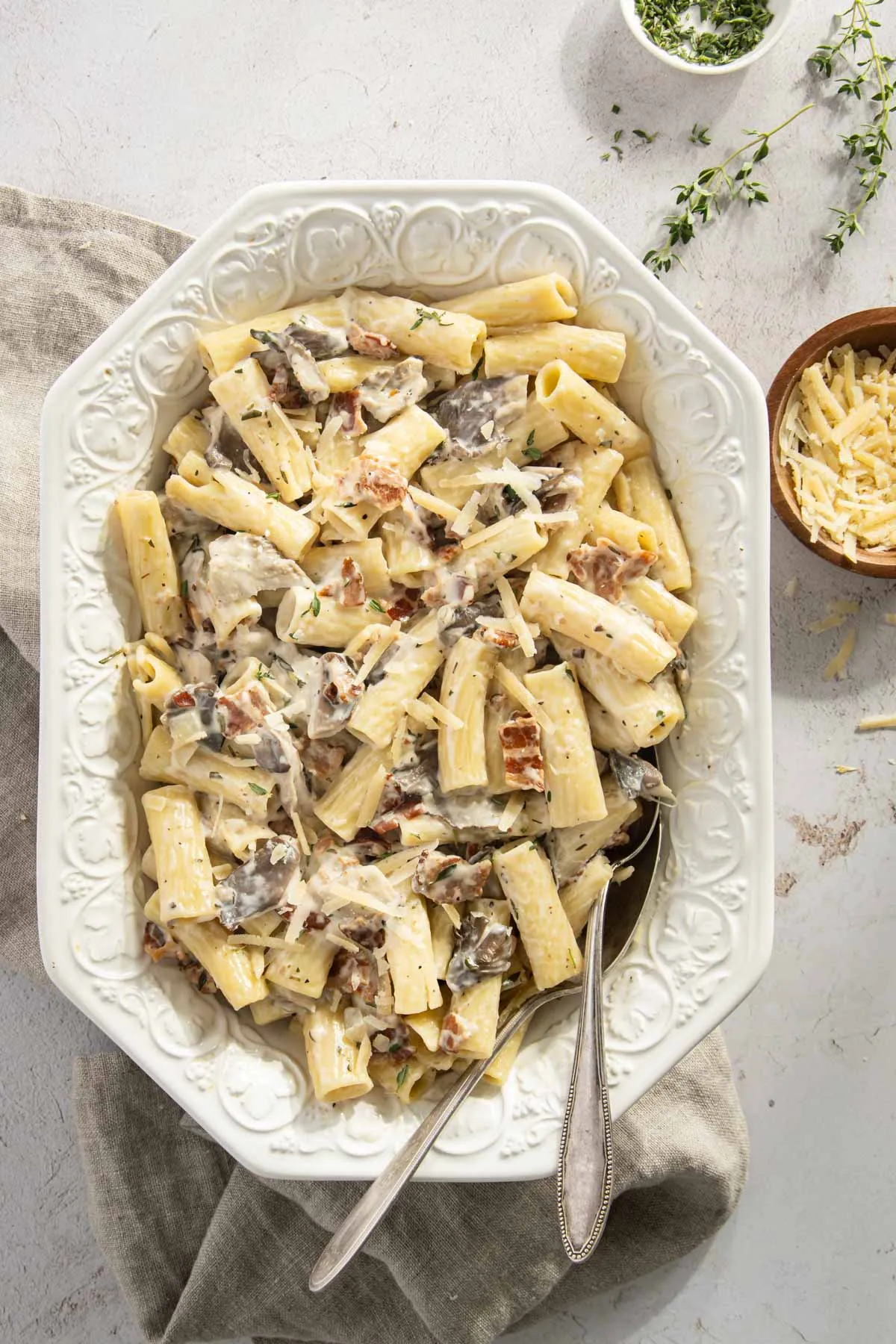 pasta in a serving dish, small bowl with shredded parmesan cheese
