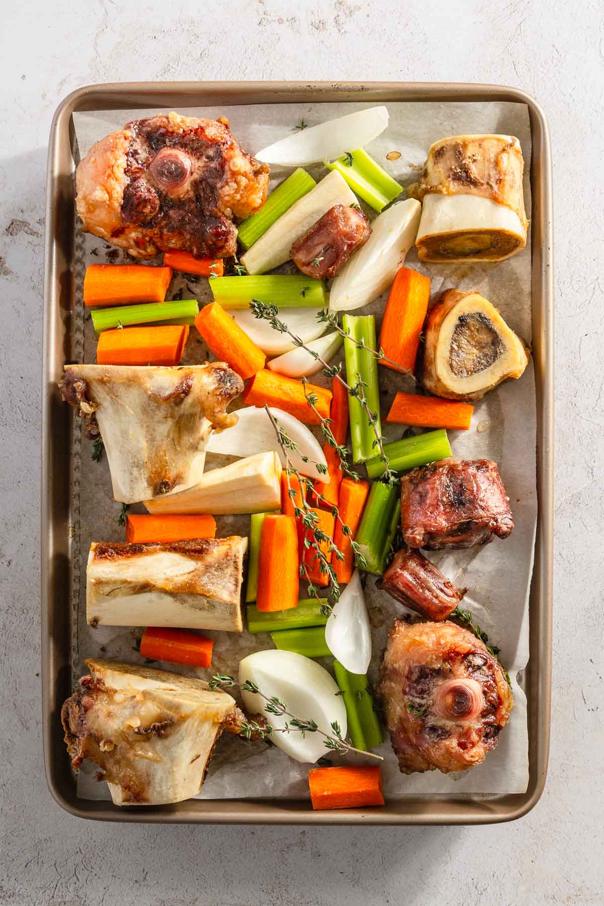 cut up veggies and roasted beef bones on a baking sheet