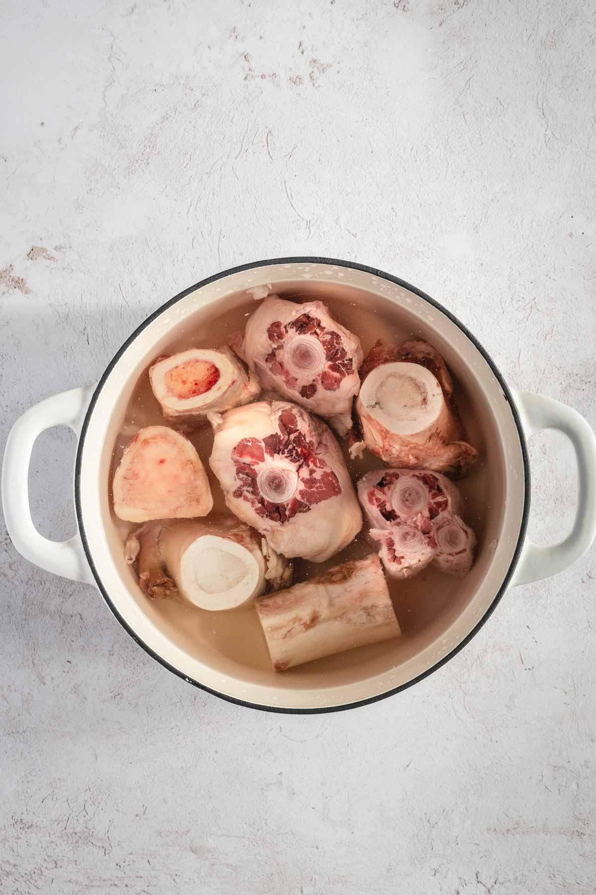 beef bones in a cooking pan filled with water