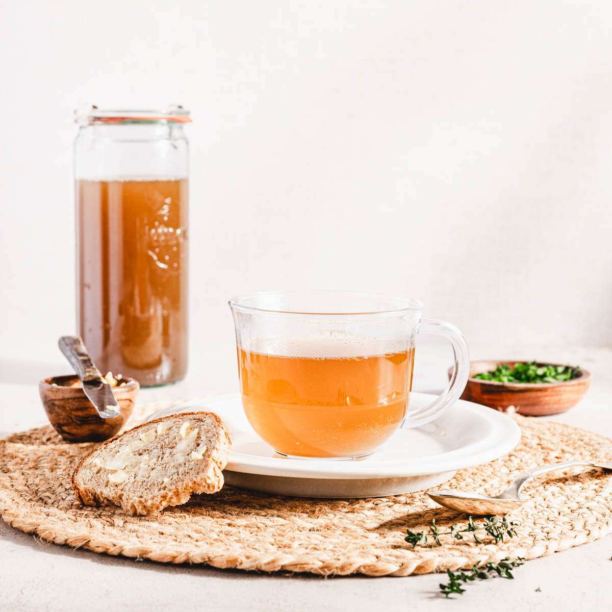 beef broth in a drinking glass, slice of bread, dish with chopped parsley