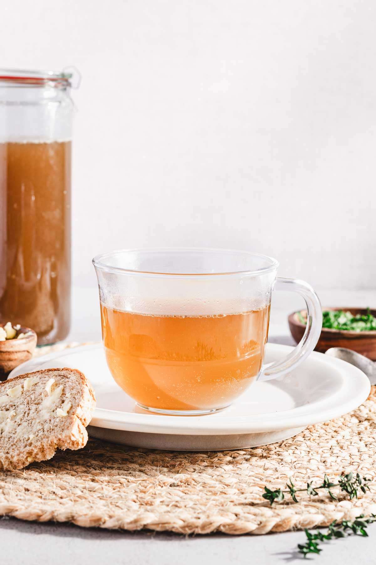 beef broth in a drinking glass, slice of bread, dish with chopped parsley