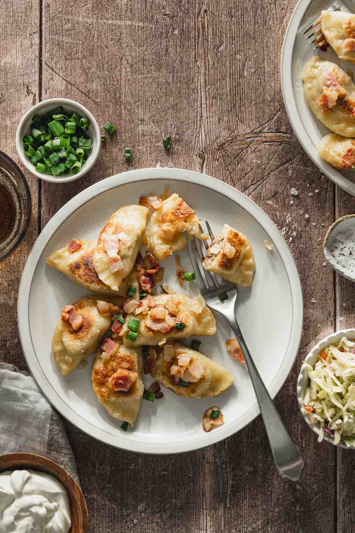 plate with cooked pierogis with bacon-onion topping and a side salad