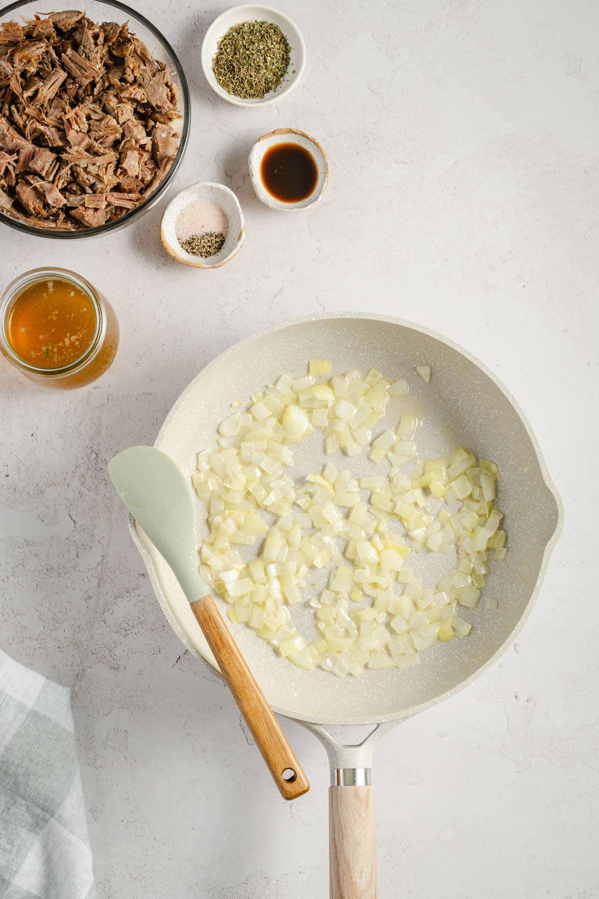 frying pan with chopped onion, small bowls with other ingredients to make the beef filling