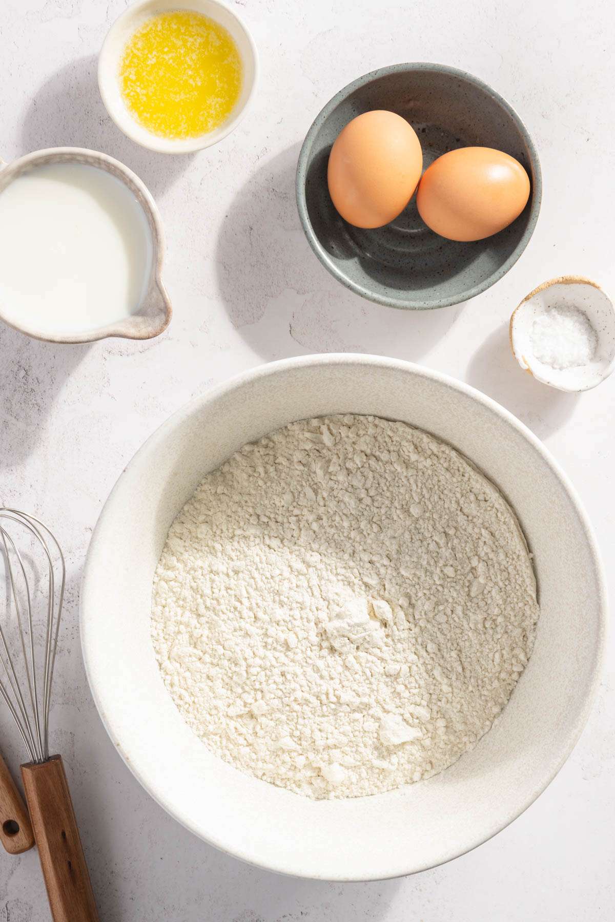 ingredients to make pierogi dough; bowl with flour, two eggs, milk, melted butter and salt