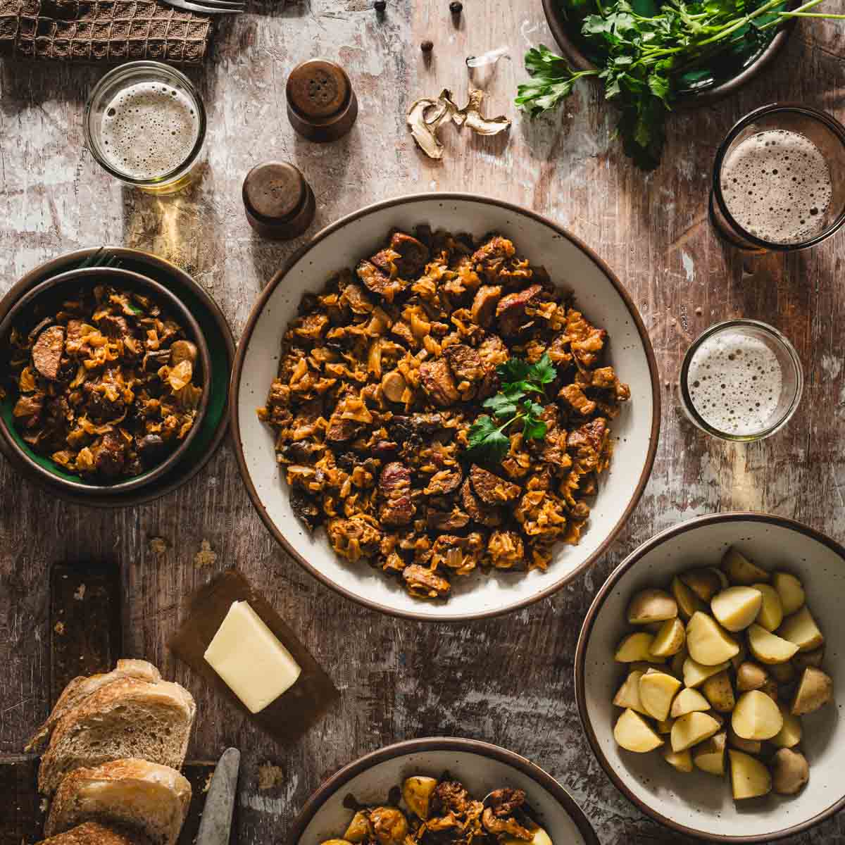 large serving bowl with bigos, slicesofbread, fresh parsley