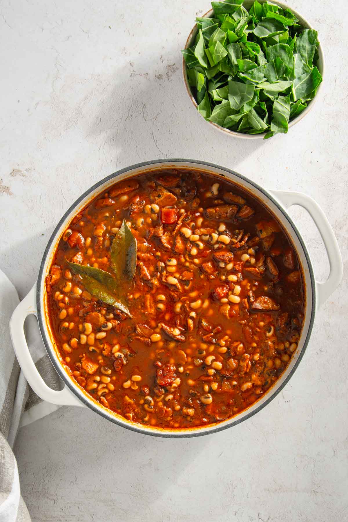 pot with cooked black-eyed pea stew; small bowl with chopped collard greens