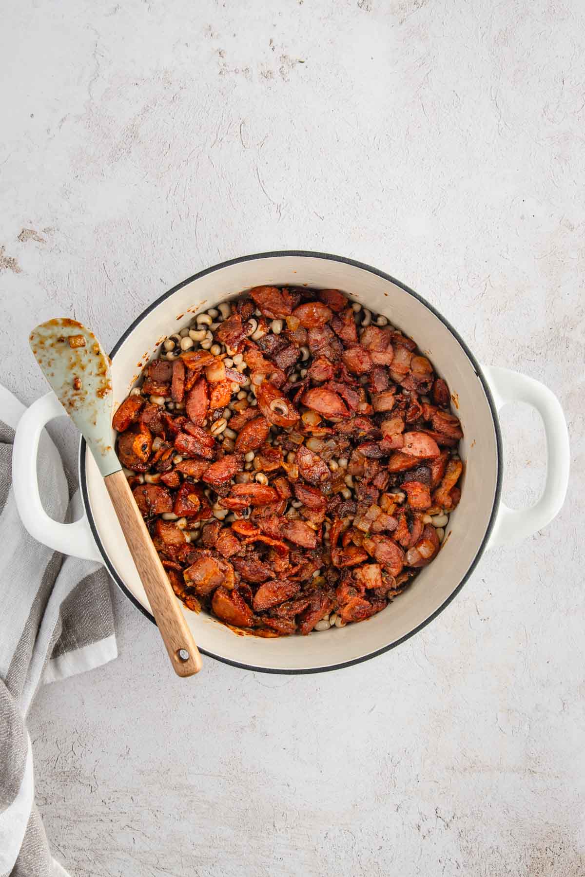 pot with black-eyed peas and bacon and sausage, mix together