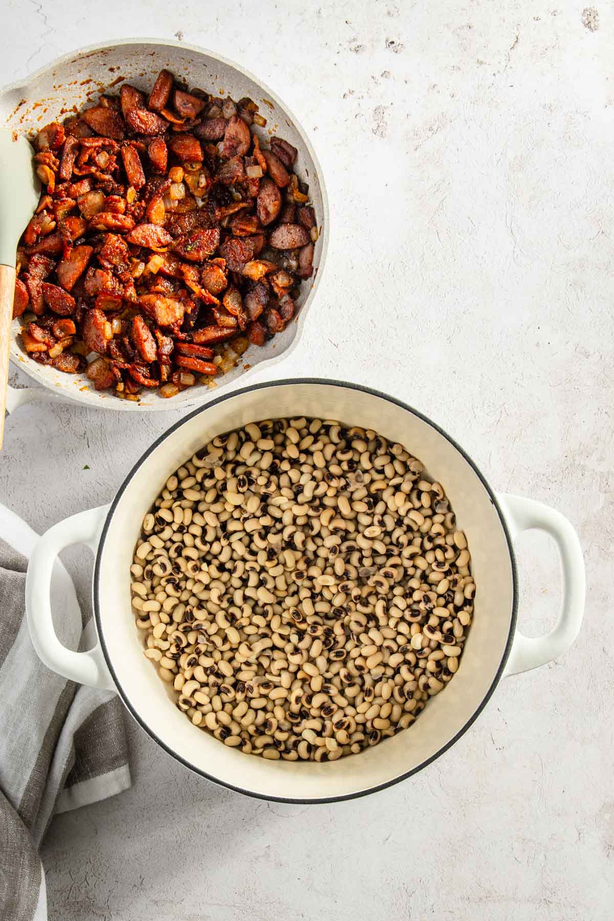 pot with black eyed peas and pot with cooked bacon and sausage