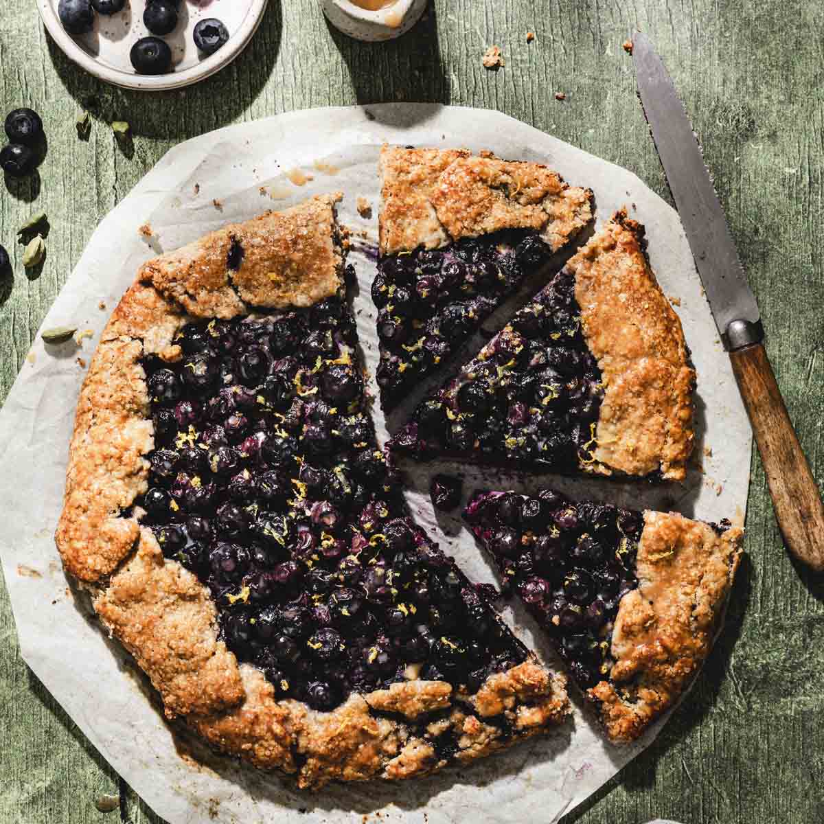 blueberry galette on parchment paper, few slices cut out