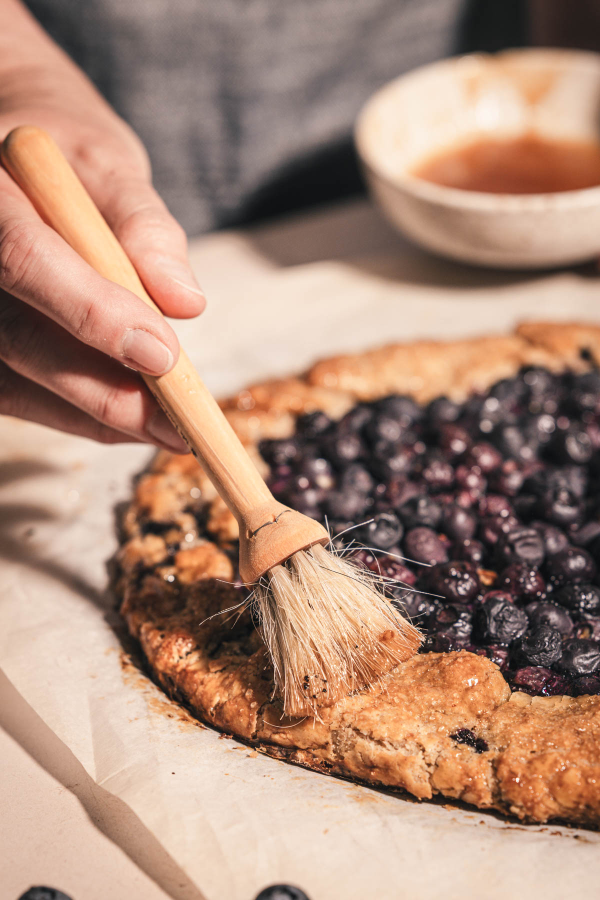 hands in frame brushing the crust using brush