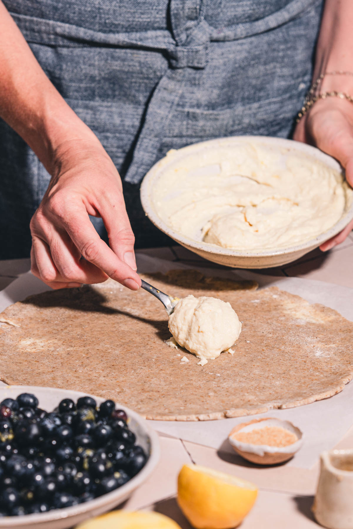 hands in frame holding spoon and spreadign the ricotta filling