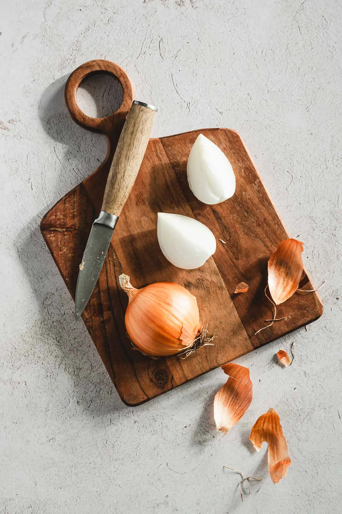 onion on a cutting board, small knife