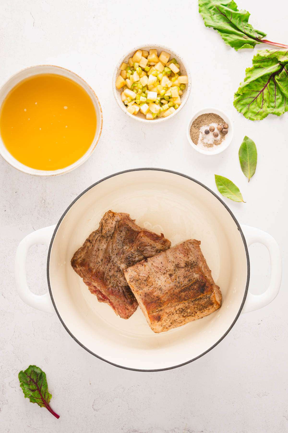 pot wqith roasted pork ribs in it; dish with broth, aromatics