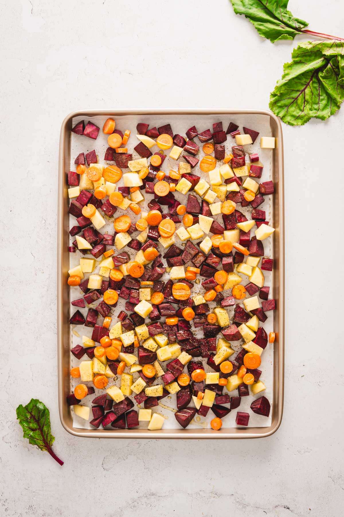 baking sheet with fresh cut up veggies drizzled with oil