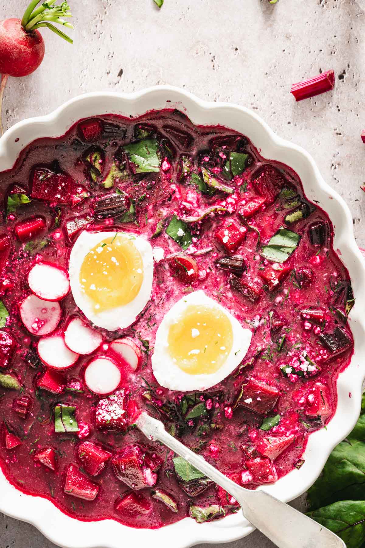 close up of botwinka soup garnished with egg, radishes