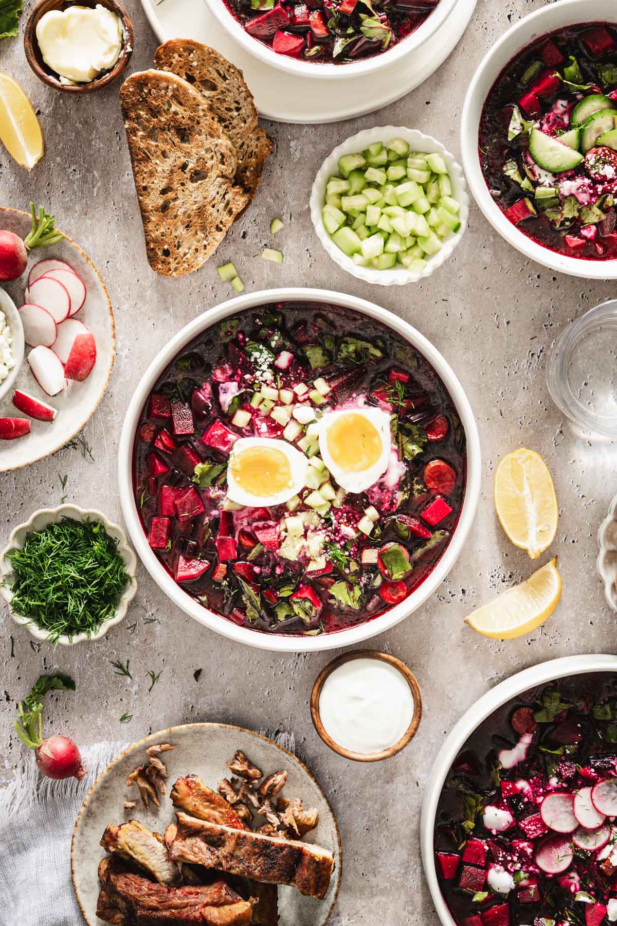 on a light background, botwinka soup in a serving bowl, garnished with an egg, beet leaves, fresh dill, cucumbers