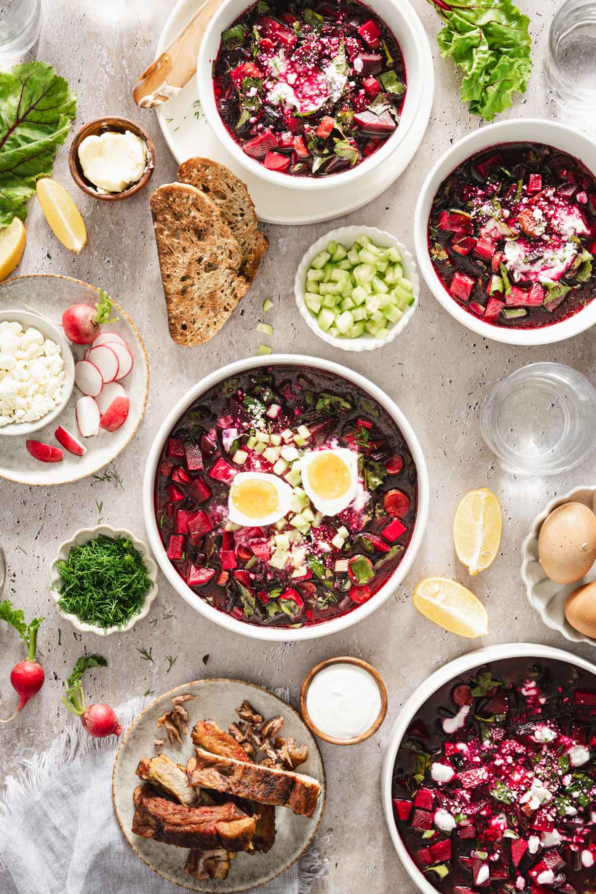 n a light background, botwinka soup in a serving bowl, garnished with an egg, beet leaves, fresh dill, cucumbers, full size scene