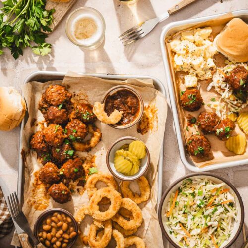 various small sheet pans with meatballs, slaad, beans, onion rings