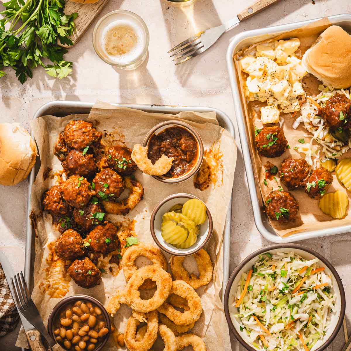 various small sheet pans with meatballs, slaad, beans, onion rings