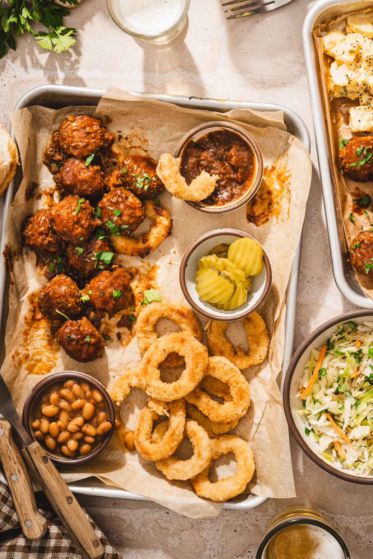close up of a serving tray with meatballs, pickles, beans, onion rings